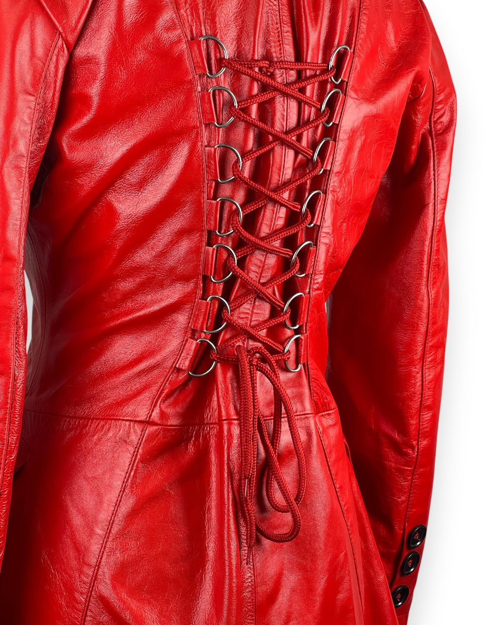 Women’s red leather coat with double-breasted military style, long tailored fit and bold statement outerwear design.